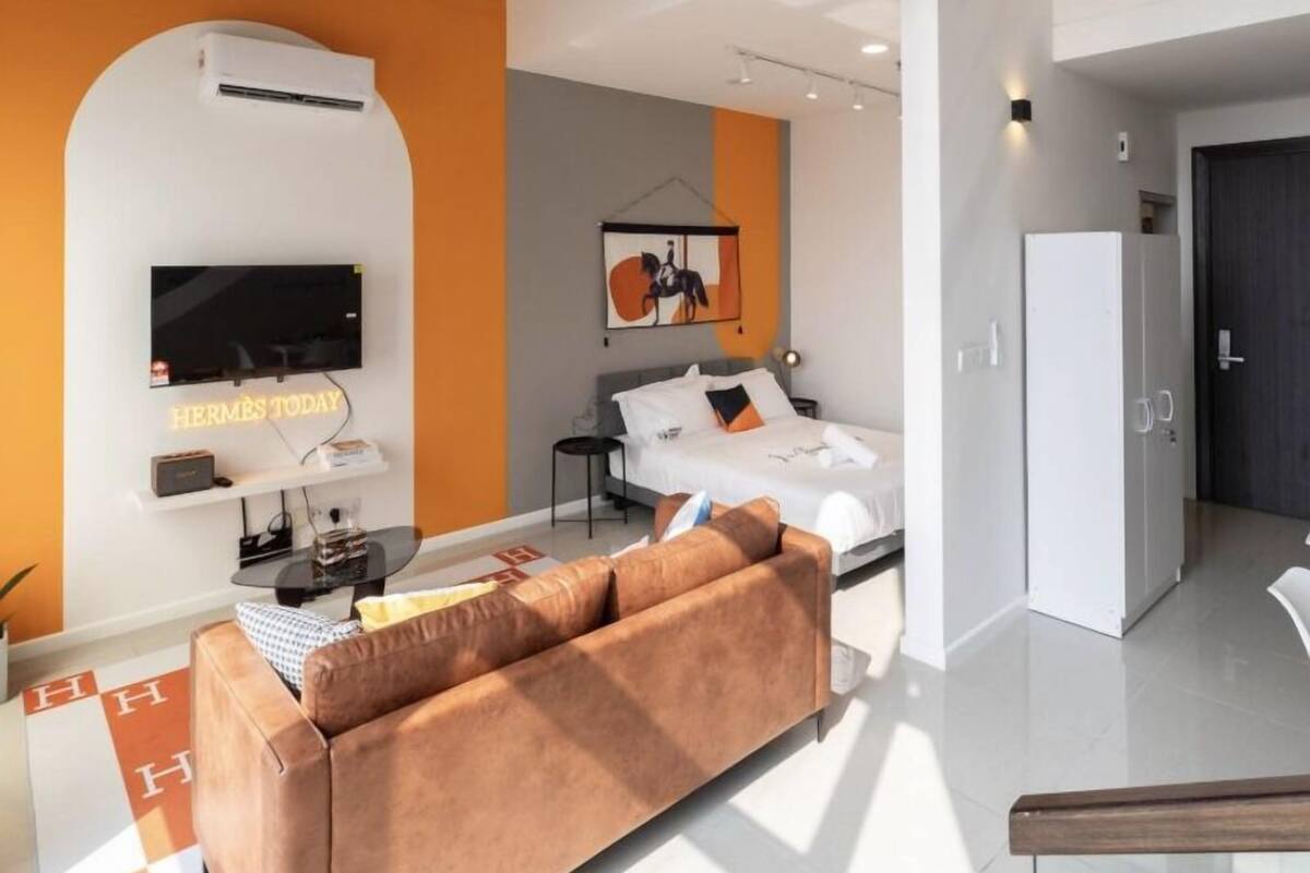 A modern living room with a sofa, a flat-screen TV, and a staircase leading to an upper level.