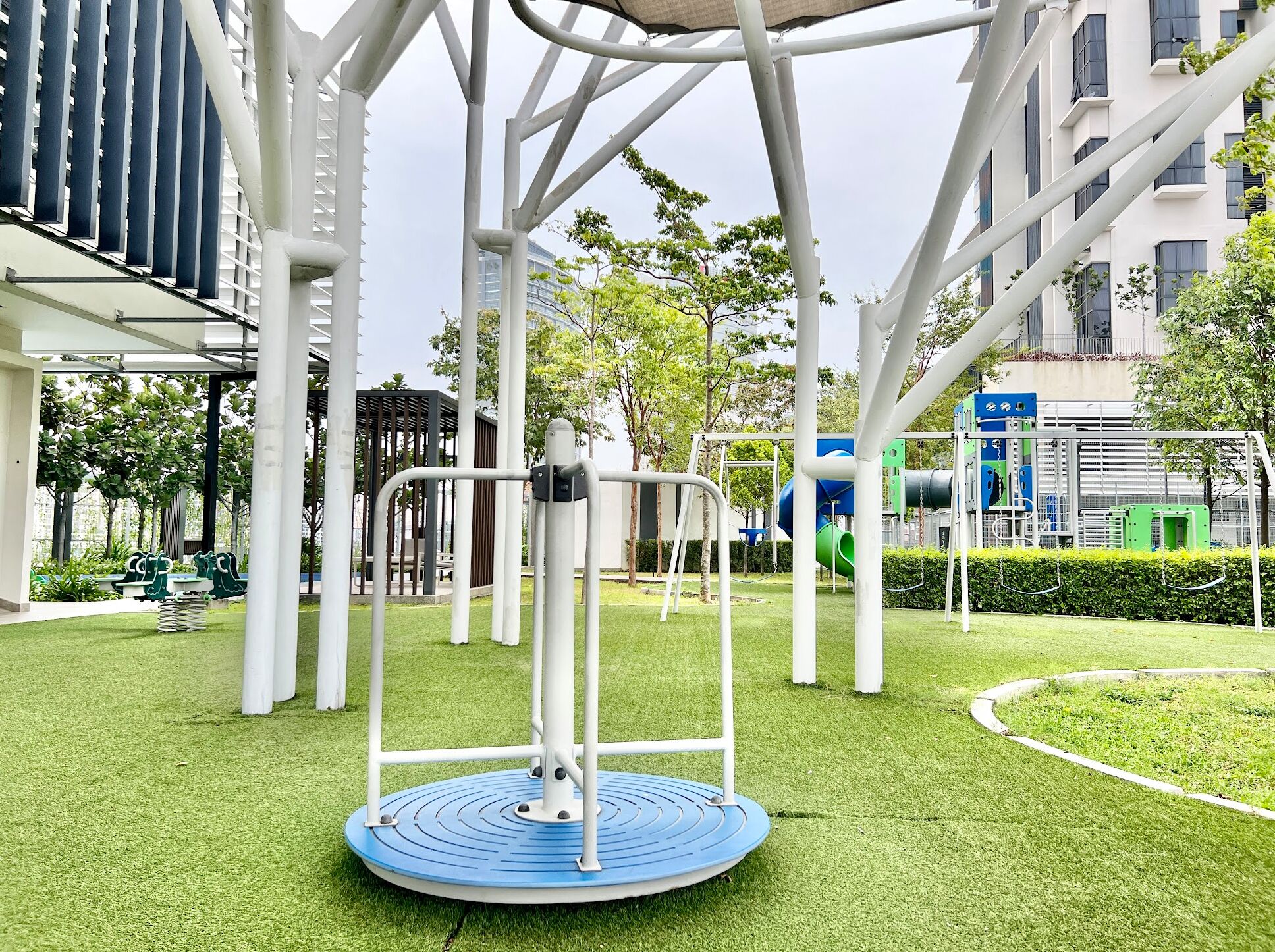 A playground with a rotating platform, swings, and a slide.