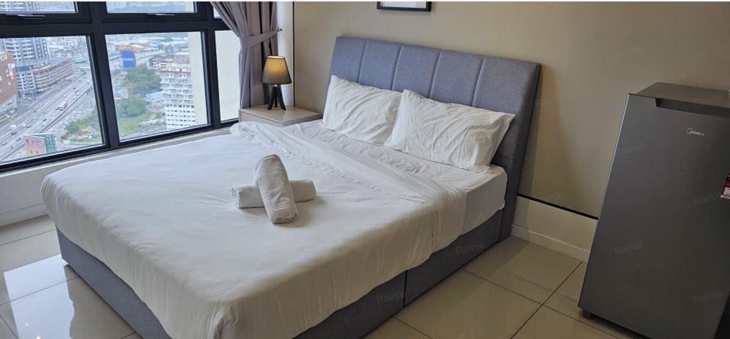 A hotel room with a bed, a nightstand, a lamp, and a view of the city.