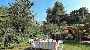 Un área de comedor al aire libre con una mesa dispuesta para dos personas, rodeada de exuberante follaje y árboles.