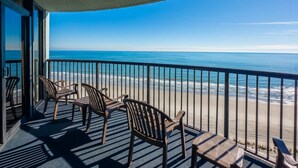 A balcony with a view of the ocean, equipped with chairs and a table. - Compass Cove Mariner 1415 (Myrtle Beach)