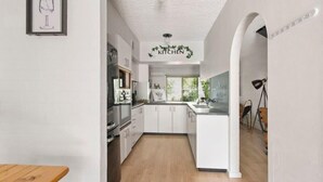 Une cuisine moderne avec des meubles blancs, un plan de travail en bois et un plafond sur lequel est inscrit le mot « CUISINE ».