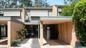 Une maison à deux étages avec un patio couvert, un petit jardin et un garage.