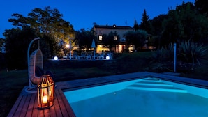 Ein Poolbereich mit Holzterrasse, Hängesessel und Laterne.