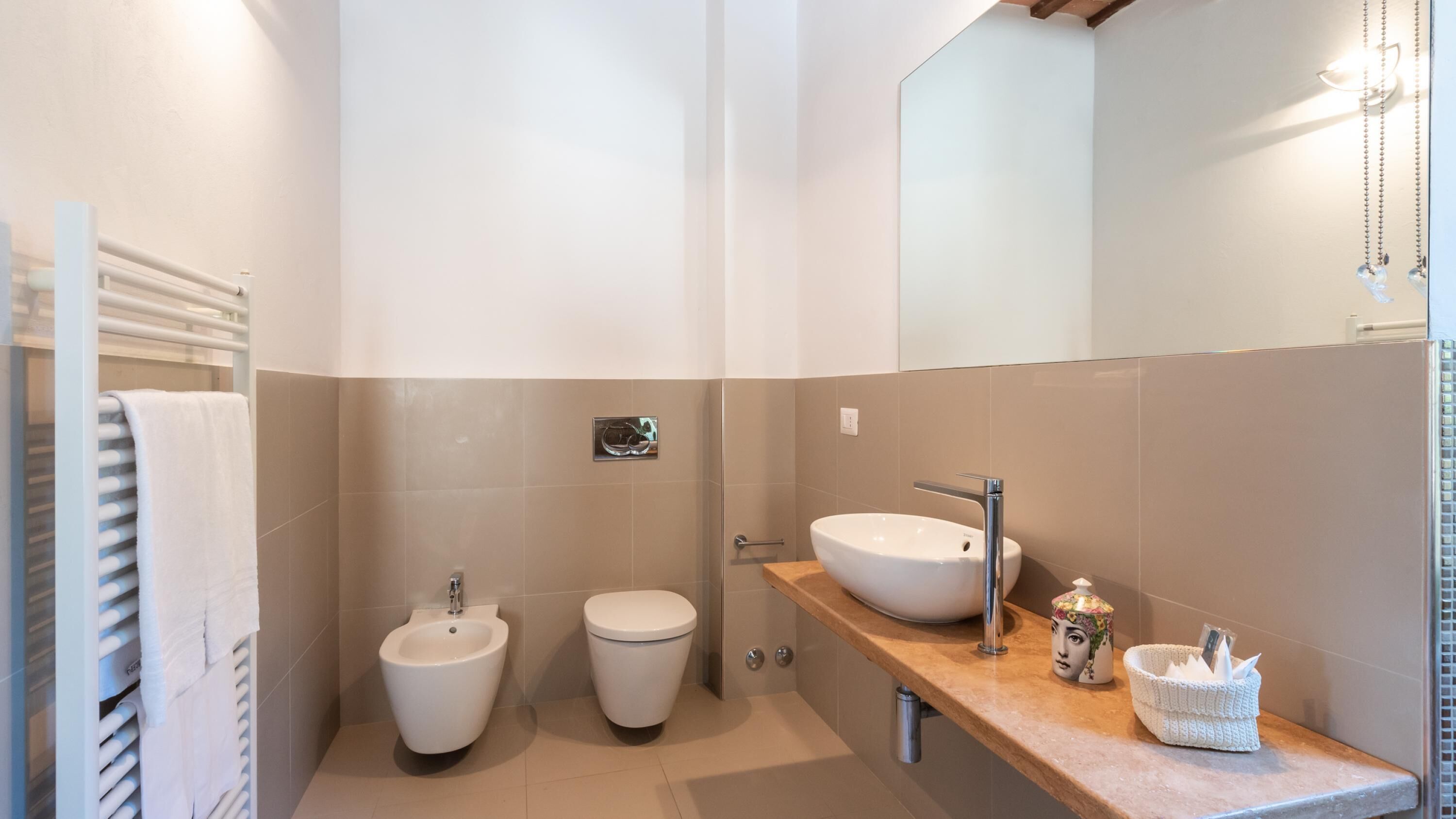 Un baño moderno con un bidé, dos inodoros, un lavamanos y un espejo.