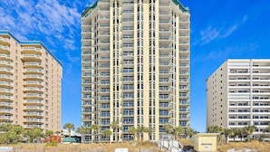 A high-rise hotel with multiple balconies, a flat roof, and a clear blue sky. - 🏖️Gulf Front~Balcony~Pool~Hot Tub~Tennis Court~2BR Jade Gem🏖️ (Destin)