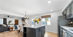 A modern kitchen with a central island, built-in appliances, and a dining area with a sofa and chairs.