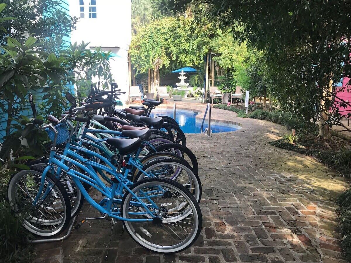 A row of bicycles parked on a brick pathway, leading to a fountain and a building in the background.
