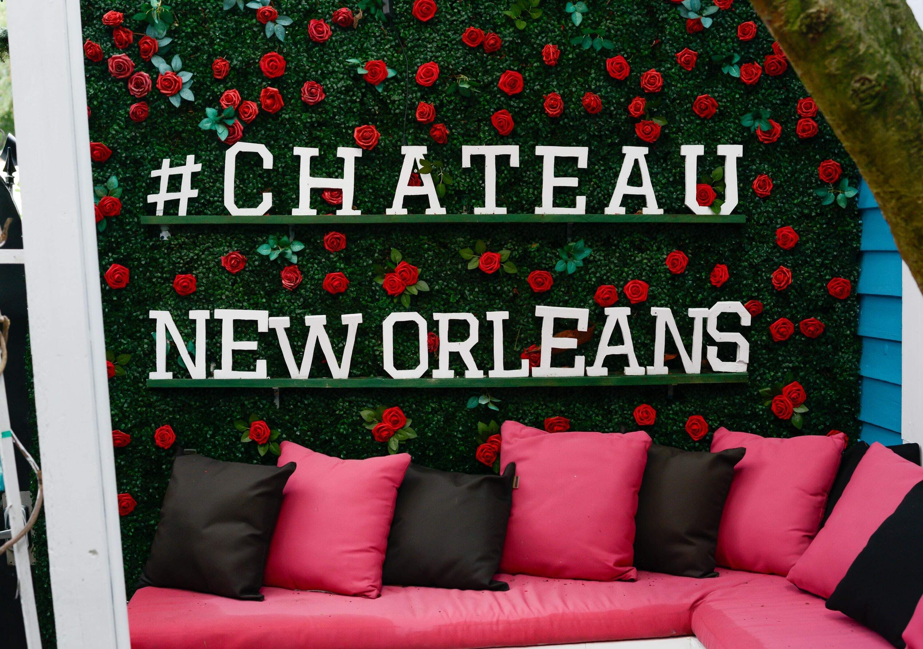 Segnaletica #CHATEAU NEW ORLEANS con uno sfondo di siepe verde e rose rosse.