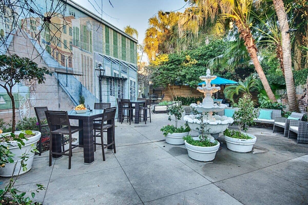 An outdoor patio with a dining area, a fountain, and potted plants.