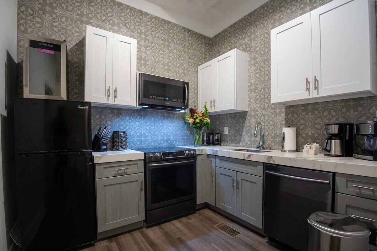 A modern kitchen with white cabinets, a black refrigerator, a microwave, and a stove.