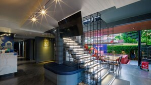 Ein modernes Interieur mit einer zentralen Treppe, einem Empfangsbereich und einer Sitzecke mit Blick ins Freie.