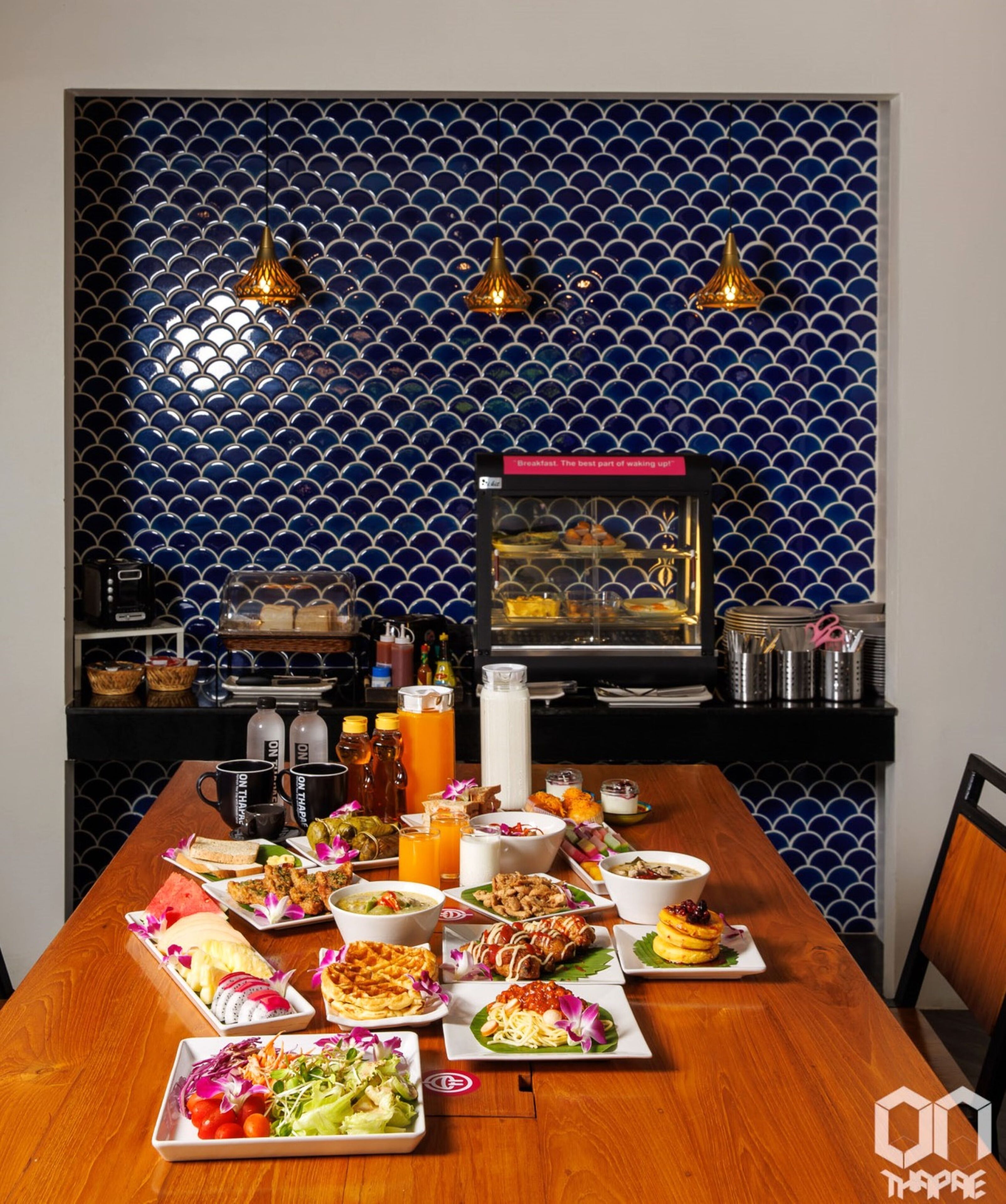 Un bufé de desayuno con una variedad de platos, una cafetera y un salpicadero decorativo de azulejos azules.