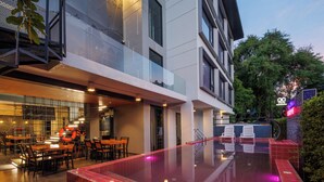 Ein modernes Gebäude mit Schwimmbad, Außenbereich zum Sitzen und einem Restaurantbereich.