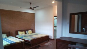 A room with two single beds, a wooden desk, a chair, a ceiling fan, and a mirror on the wall. - Windy Hanthana (Kandy)