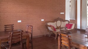 A dining area with a brick wall, wooden furniture, and a ceiling fan. - Windy Hanthana (Kandy)