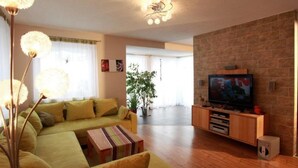 A living room with a sofa, a television, and a plant. - Beautiful group accommodation with sauna & ski-in (Itter)