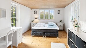 A bedroom with a bed, a desk, and a dresser.