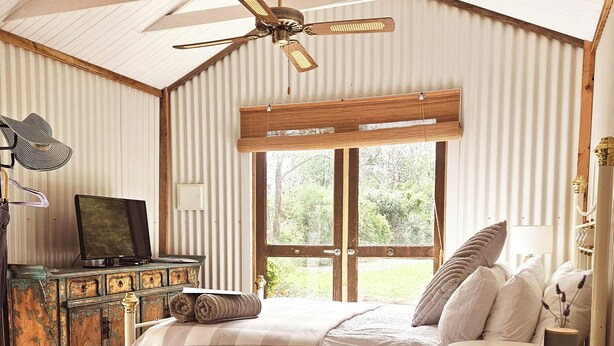 Une chambre à coucher comprenant un lit, un bureau, une chaise, un ventilateur de plafond et une fenêtre.
