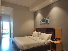 Una habitación de hotel moderna con una cama grande, una mesita de noche con un teléfono y una obra de arte colgada en la pared.