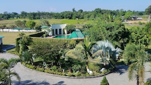 A resort with a swimming pool, lush greenery, and a white building with a green roof. - Padmini Resorts (Tinsukia)
