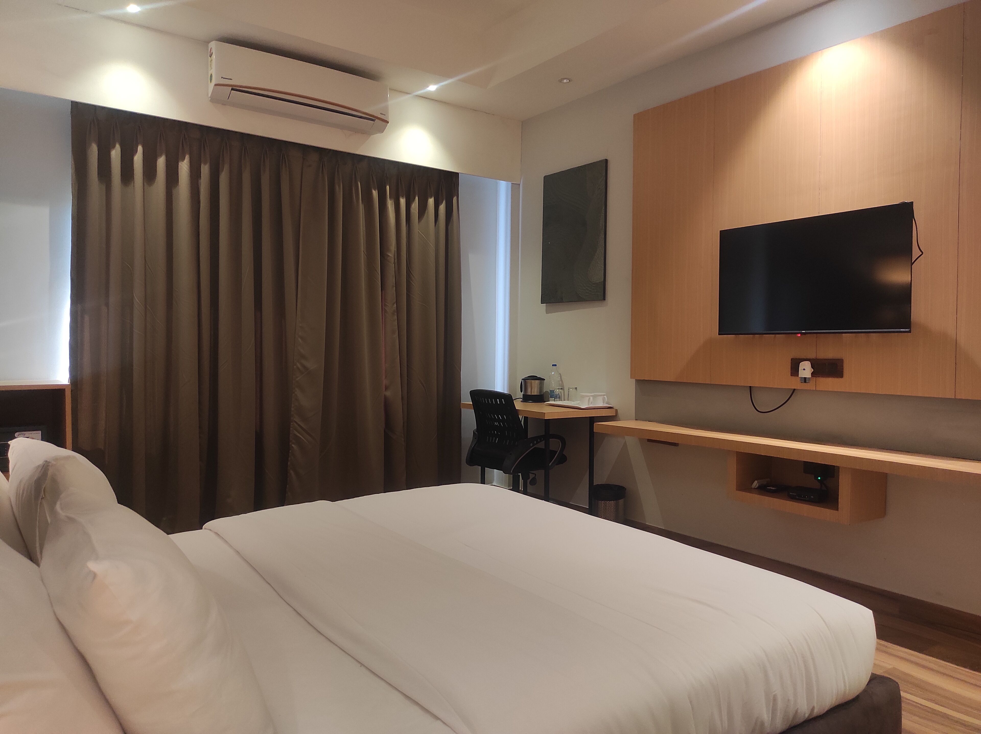 Une chambre d’hôtel équipée d’un lit, d’un bureau, d’une chaise, d’une télévision et d’un appareil de climatisation.
