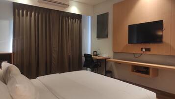 Une chambre d’hôtel équipée d’un lit, d’un bureau, d’une chaise, d’une télévision et d’un appareil de climatisation.