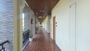 A corridor with patterned floor tiles, a stone wall on one side, and doors on the other.