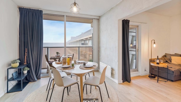 A modern living room with a dining area, large windows, and a balcony. - Sandy View - spacious studio flat near the beach (Nieuwpoort)
