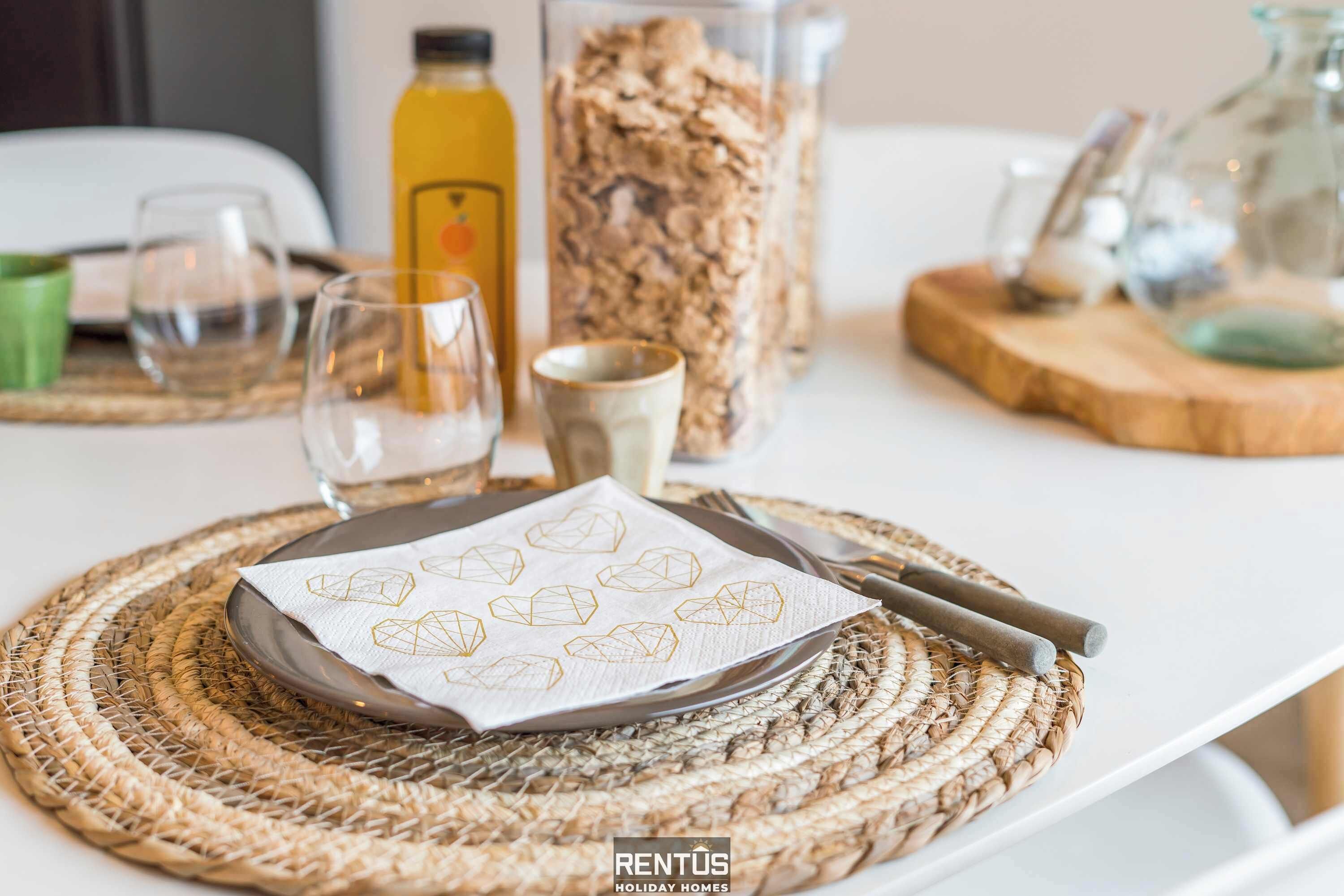 Una mesa dispuesta con una alfombrilla, una servilleta, un vaso y una botella.
