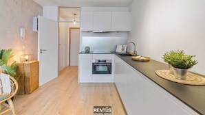A modern kitchen with white cabinets, a built-in oven, and a countertop. - Sandy View - spacious studio flat near the beach (Nieuwpoort)