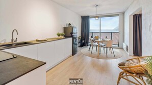 A modern kitchen with a dining area, large windows, and a balcony. - Sandy View - spacious studio flat near the beach (Nieuwpoort)