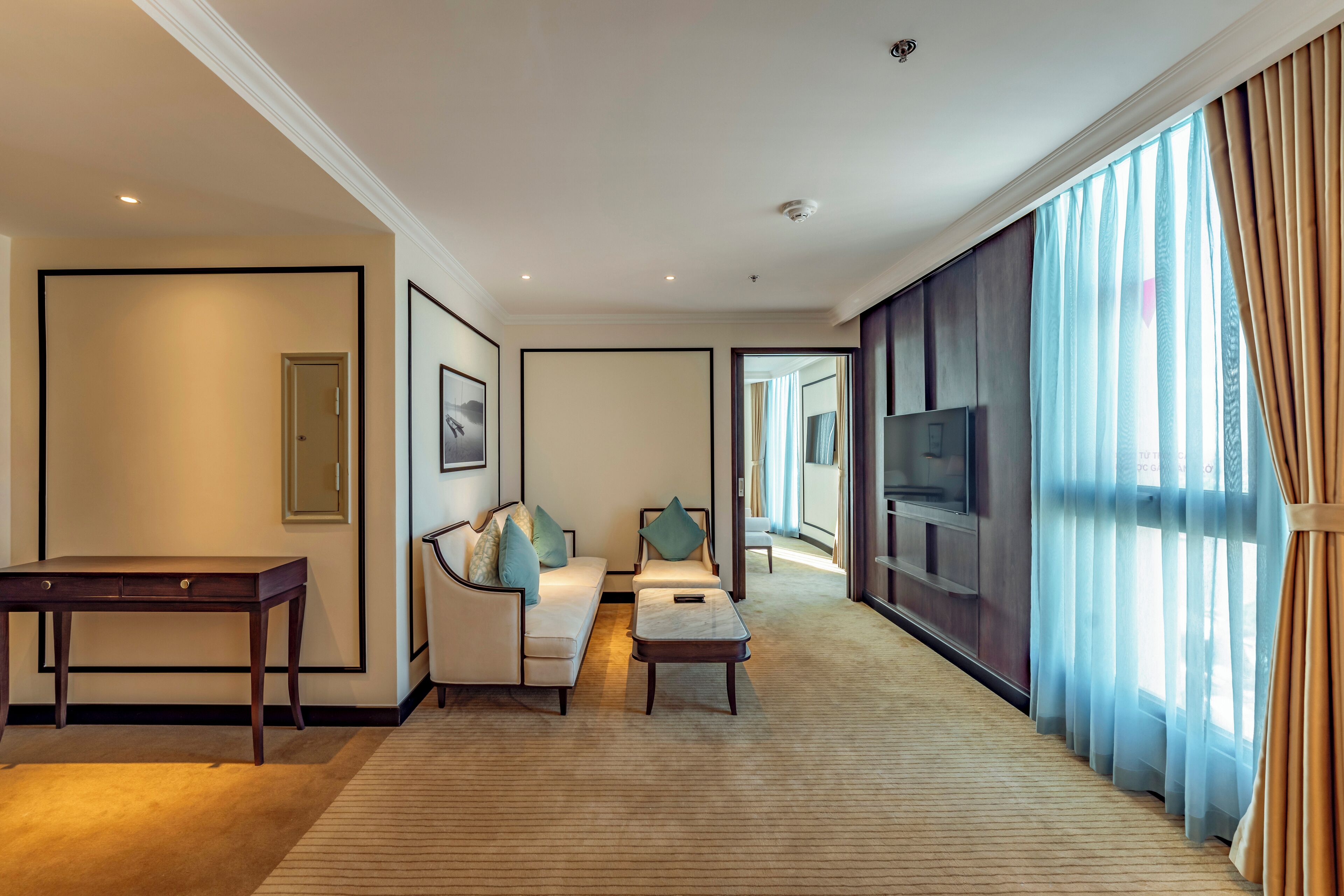 Una habitación de hotel con sofá, sillón, mesa de centro y televisor.