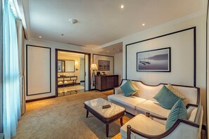 A modern hotel room with a sofa, armchairs, a coffee table, and a large framed picture on the wall. - Charmant Suites a Boutique Hotel Can Tho (Can Tho)