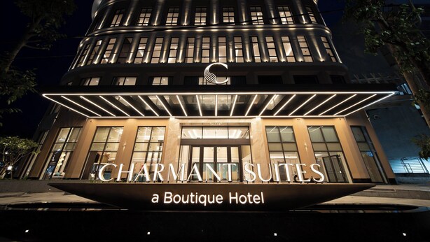 A modern building with a prominent sign for 'CHARMANT SUITES Boutique Hotel'.
