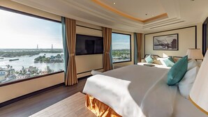 A hotel room with a large bed, a TV, and a view of a river and bridge.