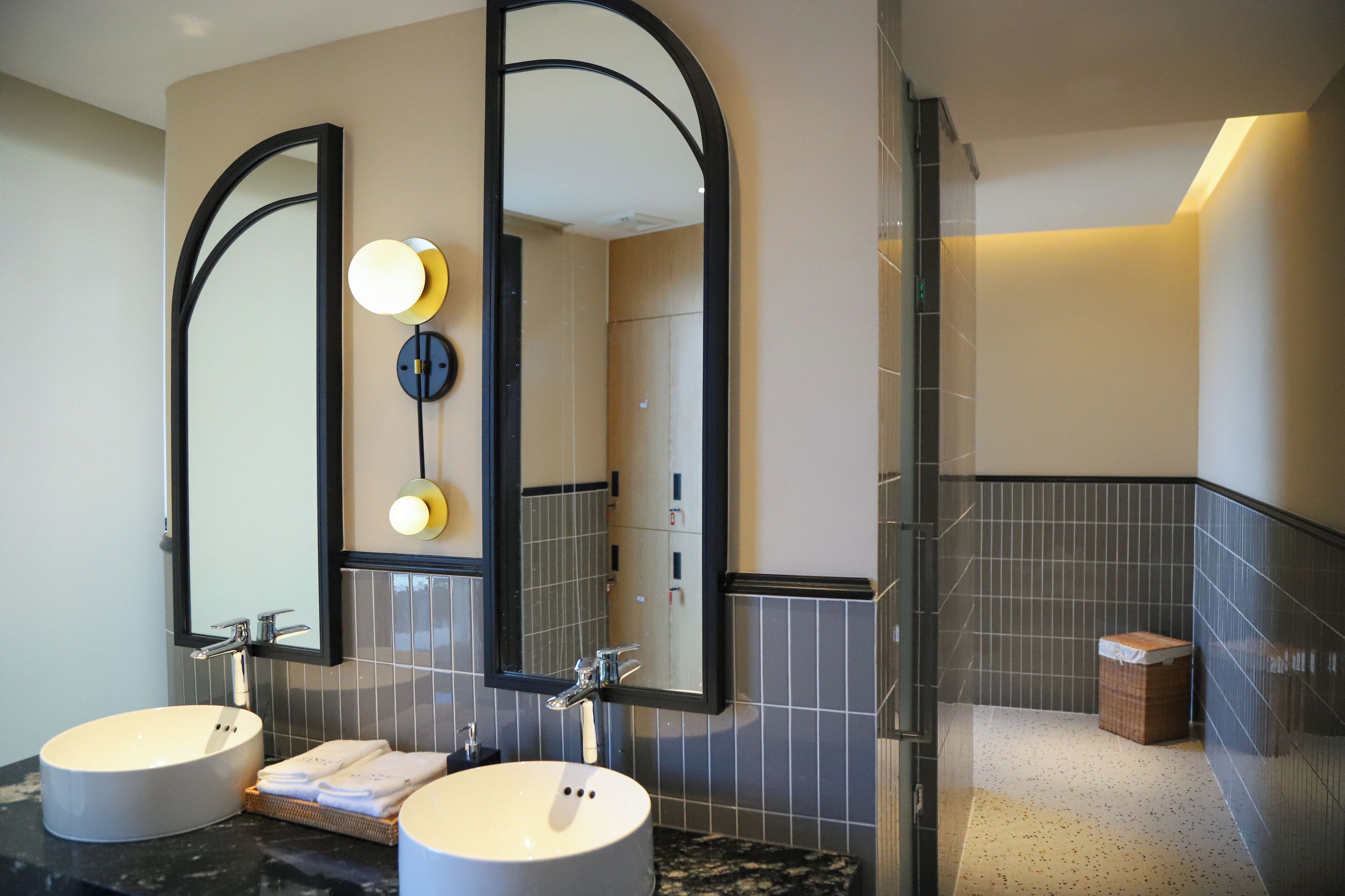 Une salle de bain moderne avec deux lavabos, de grands miroirs et un espace douche.