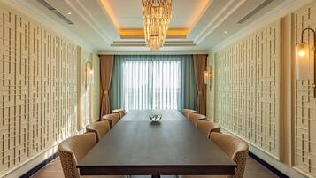 A conference room with a long table, leather chairs, a chandelier, and patterned walls.