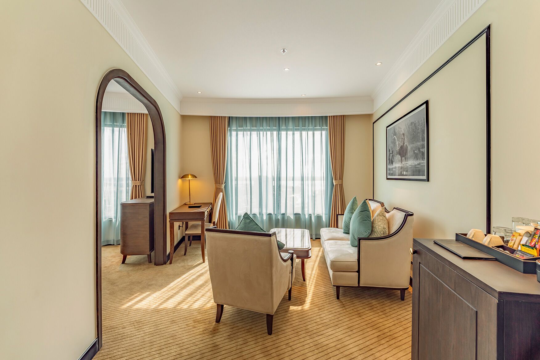 Habitación de hotel con sofá, sillones, escritorio y mesa de comedor.