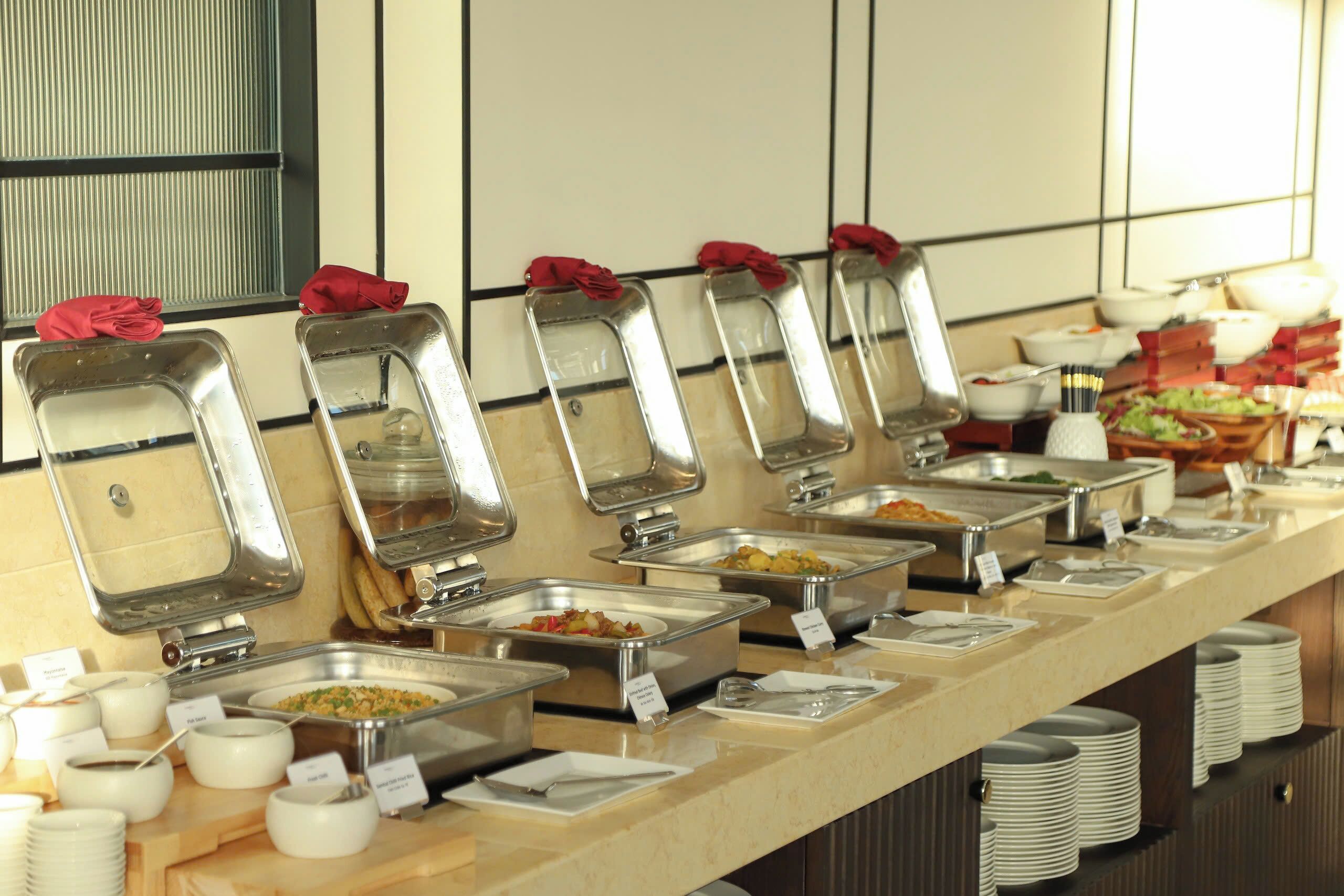 Un buffet avec plusieurs présentoirs de plats et des ustensiles de service.