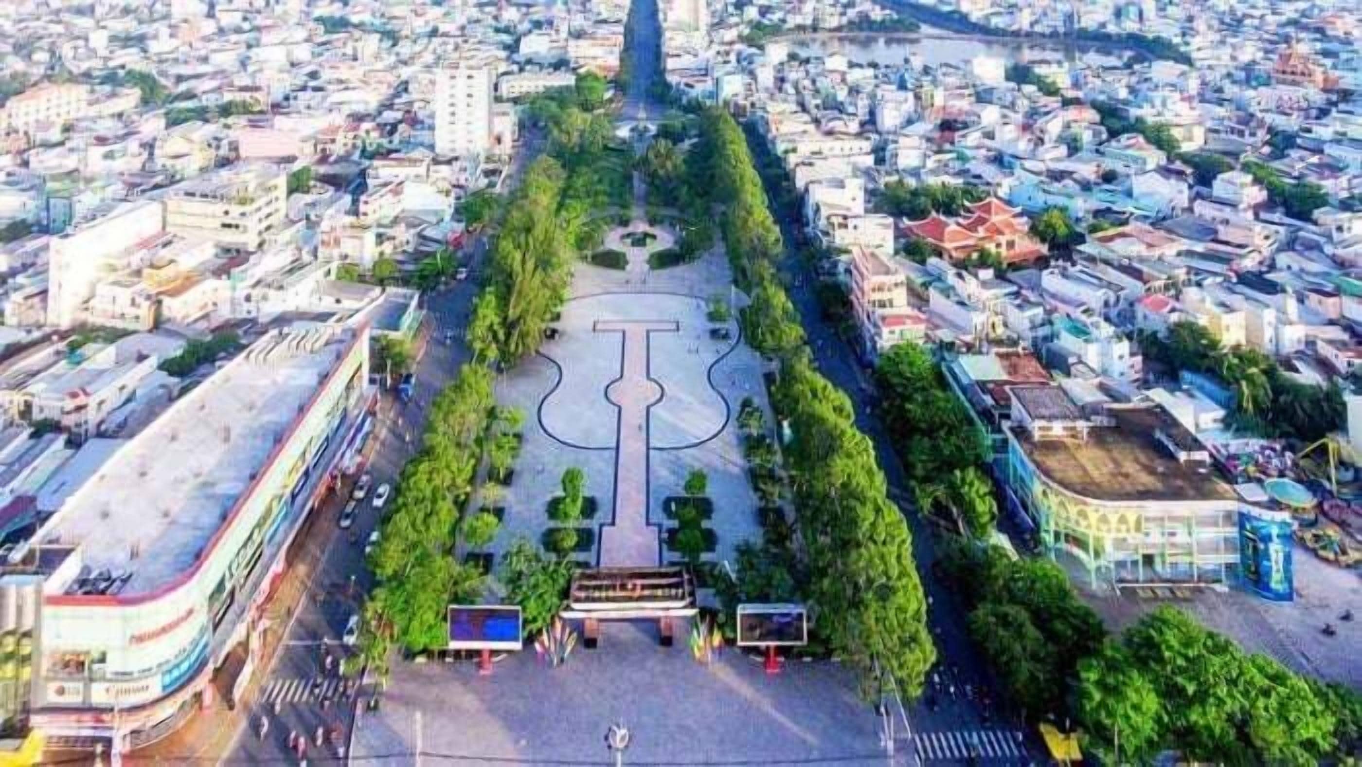 An aerial view of a city with a central park featuring a large, modern sculpture.