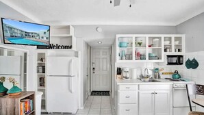 A modern kitchen with white cabinetry, a built-in microwave, and a coffee maker. - The Cozy Pelican Studio! Just Steps to the Sand! (Hollywood)