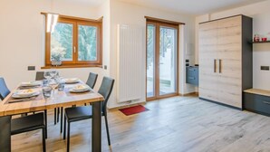 Une cuisine moderne avec une table et des chaises en bois, un meuble encastré et une porte-fenêtre coulissante donnant sur un balcon.