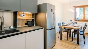 Une cuisine moderne dotée d’un réfrigérateur en acier inoxydable, d’un plan de travail en bois et d’un coin repas avec une table et des chaises.