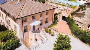 Un edificio amplio con techo de tejas, piscina y un patio cubierto.