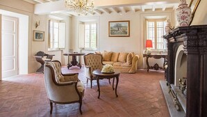 Un amplio salón con chimenea, un candelabro y un ventanal grande.