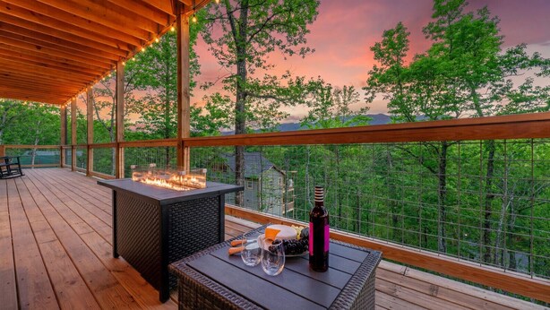 Una terraza de madera con una chimenea, asientos exteriores y una botella de vino.