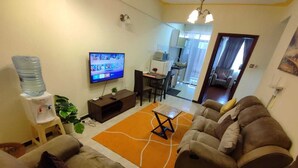 Een woonkamer met banken, een salontafel, een televisie en een waterdispenser.