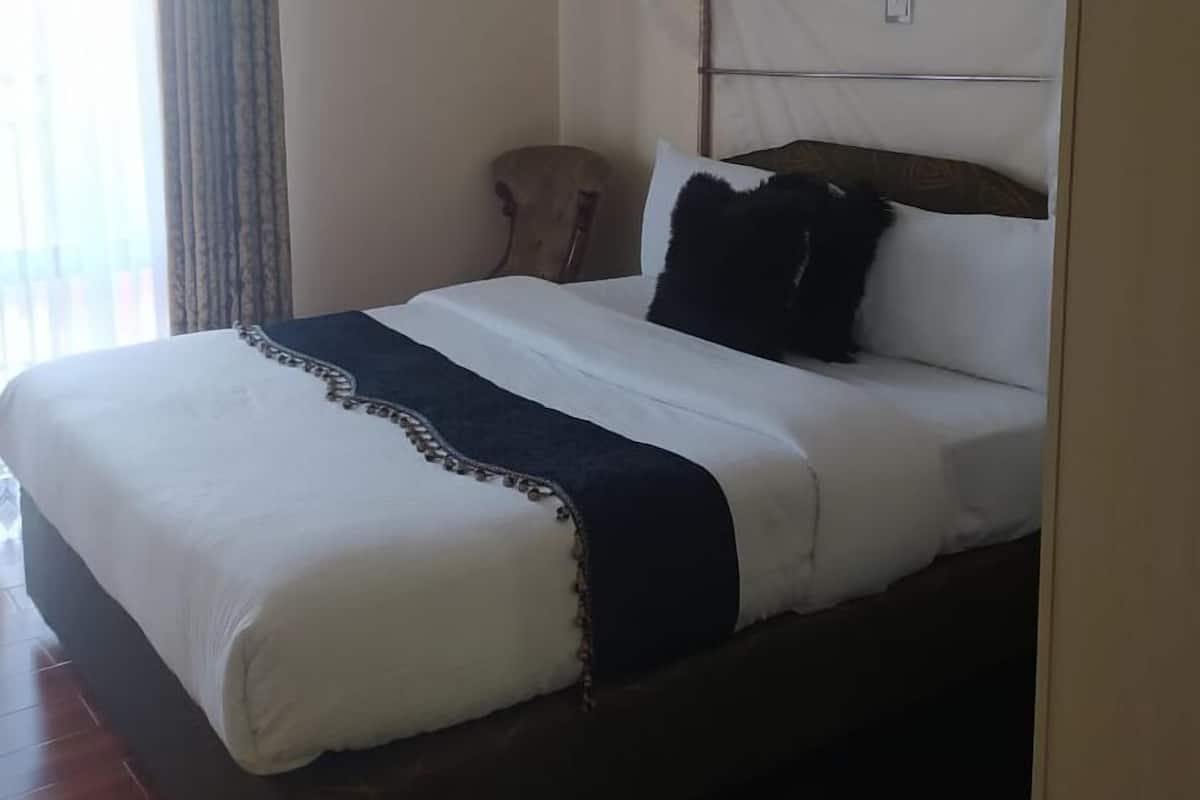 A bed with a white and navy blue bedspread, a wooden headboard, and a canopy.
