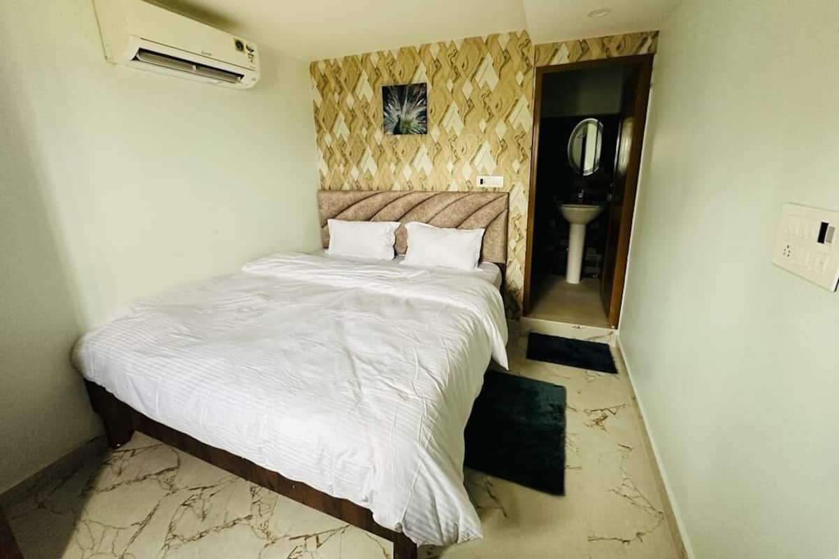 Quarto com cama, ar condicionado, parede estampada e porta de banheiro.